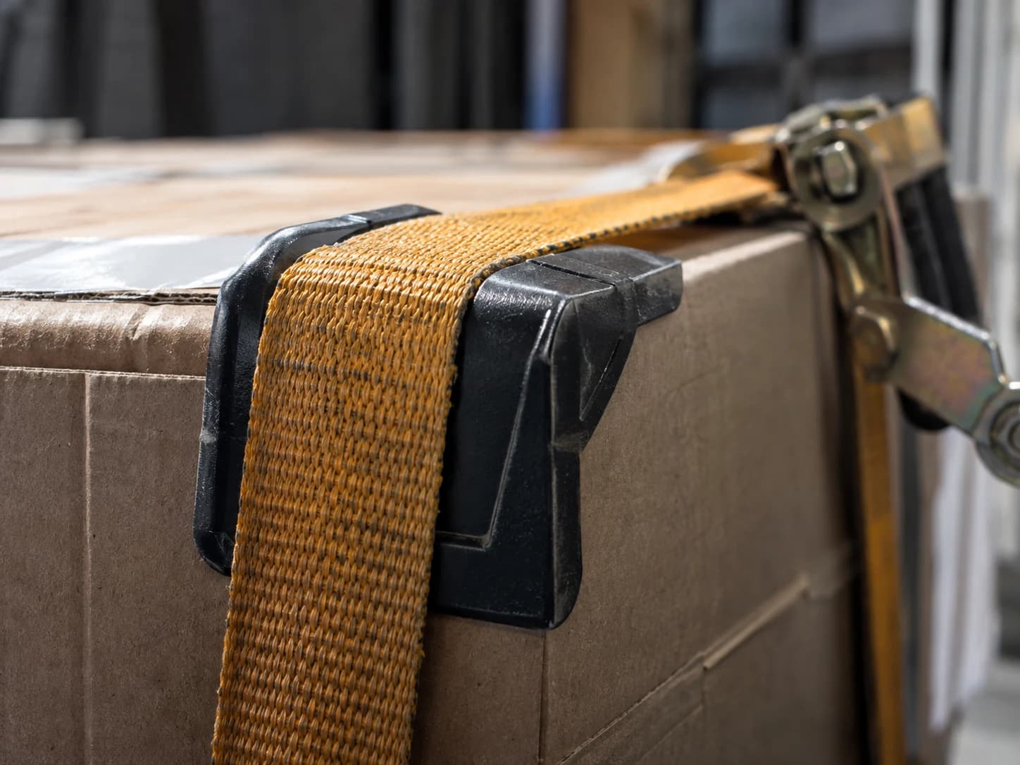 Textile webbing and protective corner board on a secured freight carton